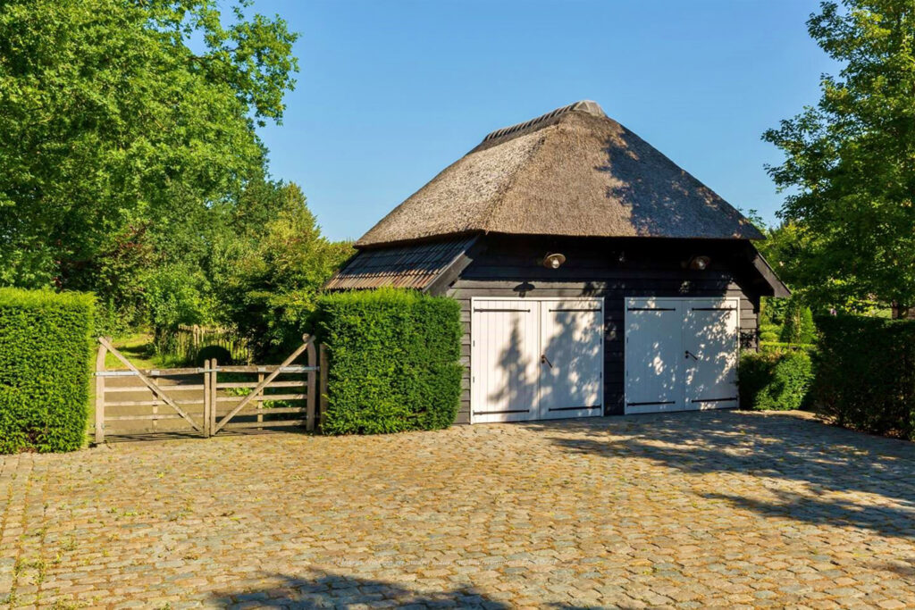 Karakteristieke schuur met rieten dak in een landelijke tuin.